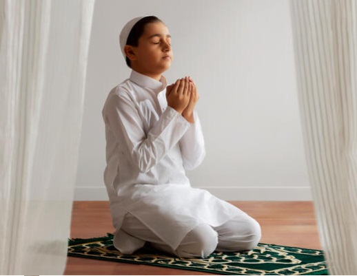 Muslim young kid reading Quran (Holy Book) and holding prayer beads - high key